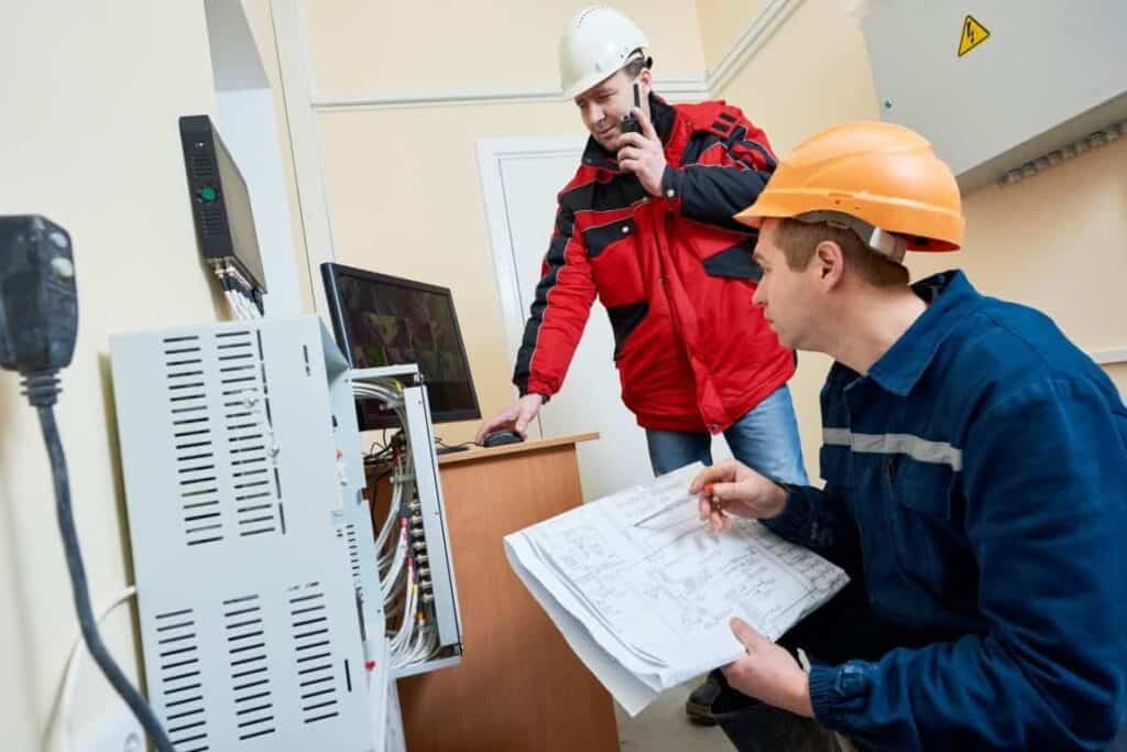 Technicians inspecting network cabling and electrical systems with safety helmets.