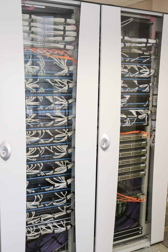 High-quality network data cabling cabinet with organised white and orange cables for reliable connectivity.