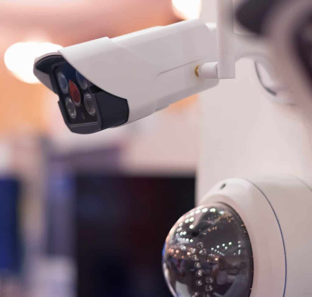 Close-up of a modern CCTV security camera with white casing, mounted on a device for surveillance.