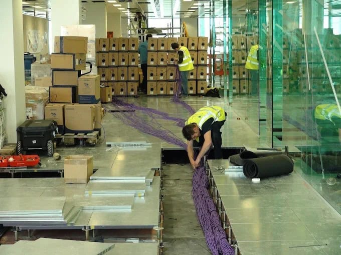 Technicians installing structured data cabling in an office environment.
