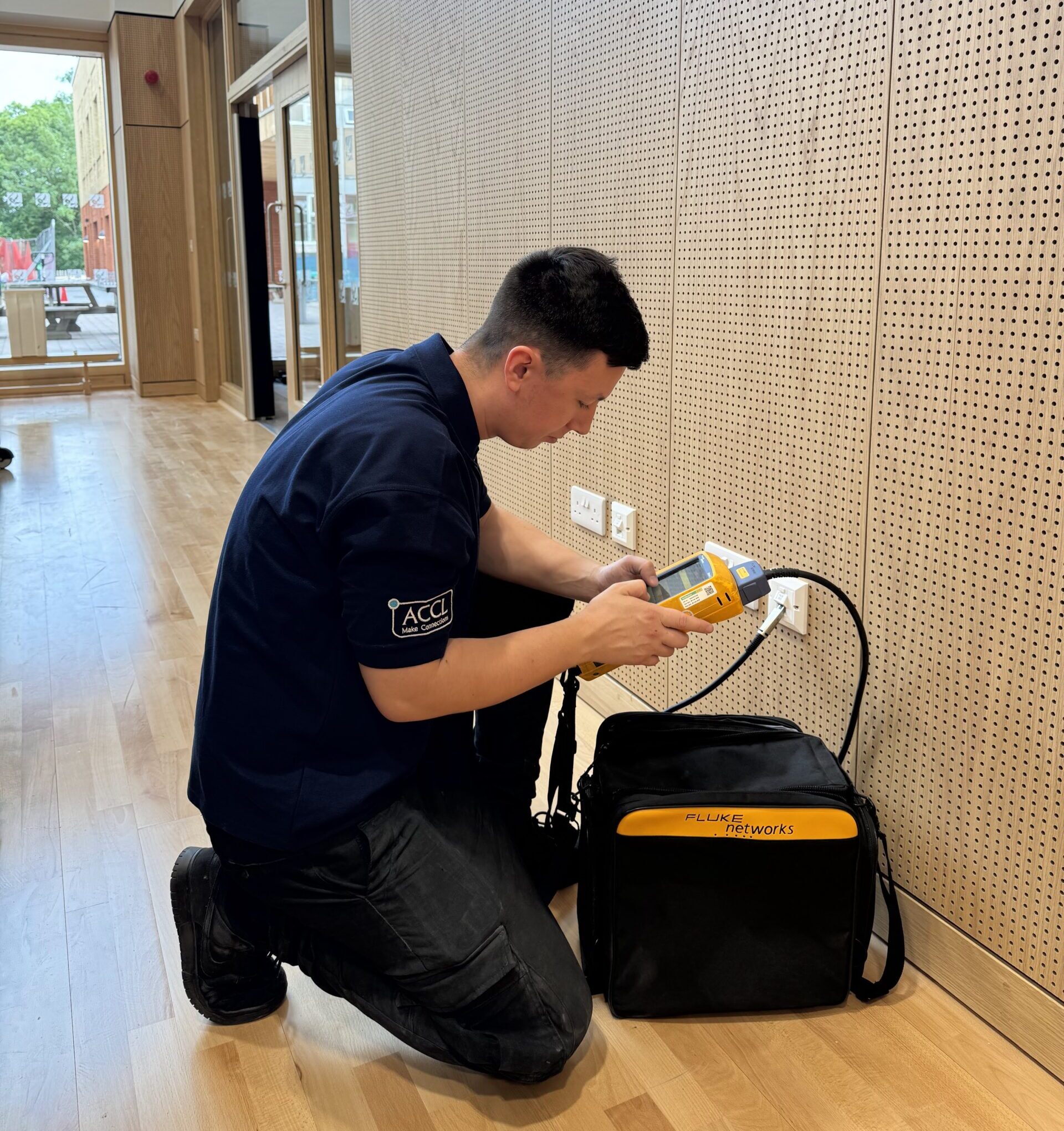ACCL engineer completing Fluke cable certification testing at a commercial data outlet