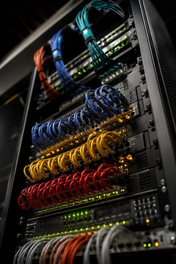 Close-up of a professional data cabinet with neatly dressed coloured patch leads, Velcro ties and glowing network status lights.