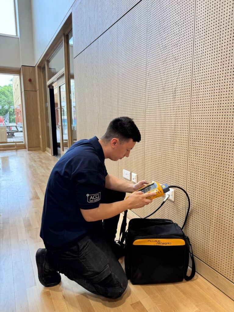 ACCL engineer certifying Cat6A cabling with a Fluke Networks tester in the finished junior school building