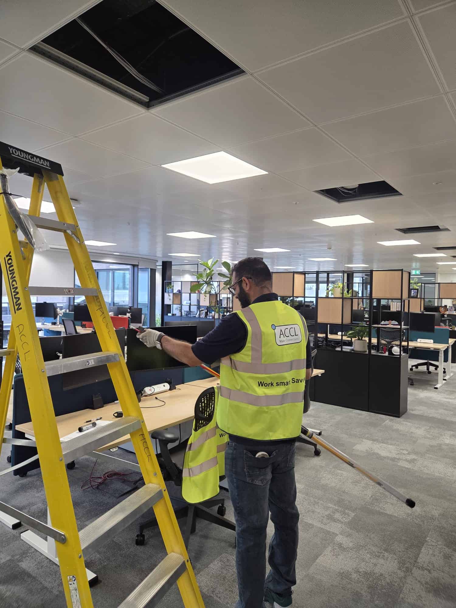 ACCL engineer installing cabling at a desk position on Level 5 of Gard's office