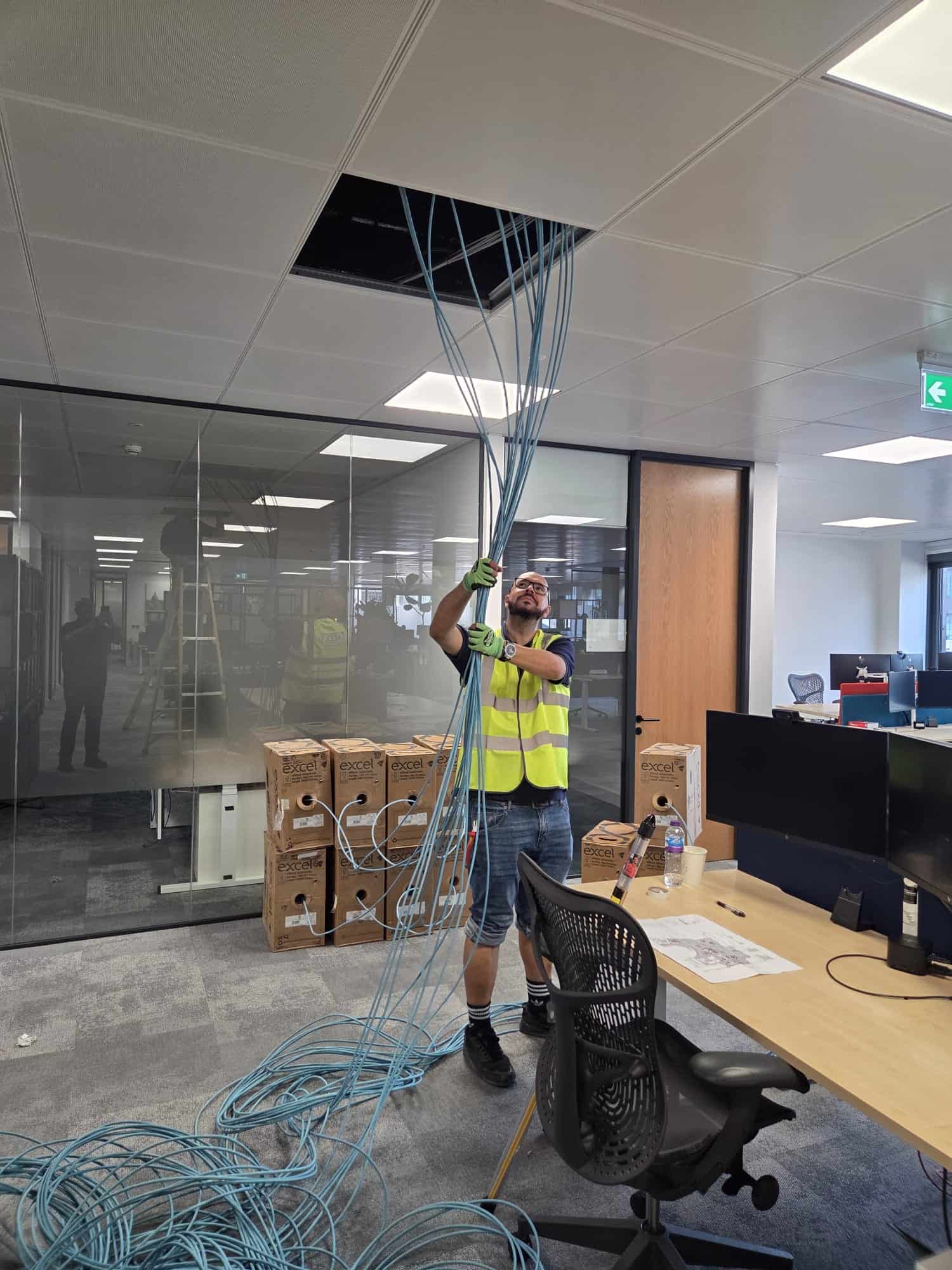 ACCL engineer pulling a bundle of Excel Cat6A cables through the ceiling void at Gard's Level 5 office