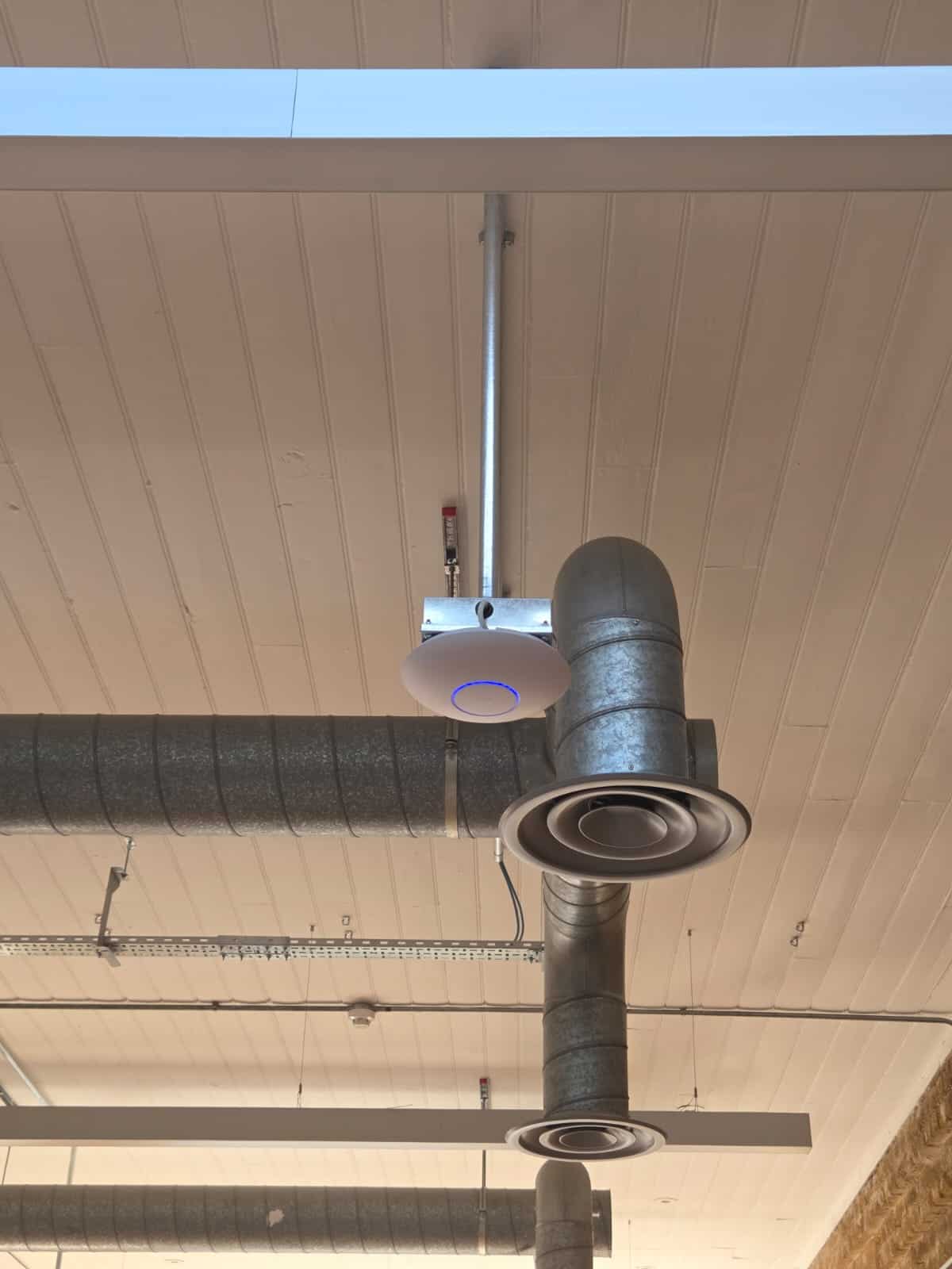 Wi-Fi 7 access point installed alongside surface containment and ductwork at Tidraw's office