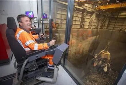 Crane operator inside the control cabin at Kent Enviropower's Allington plant, working the grab crane controls while looking out over the waste storage silo