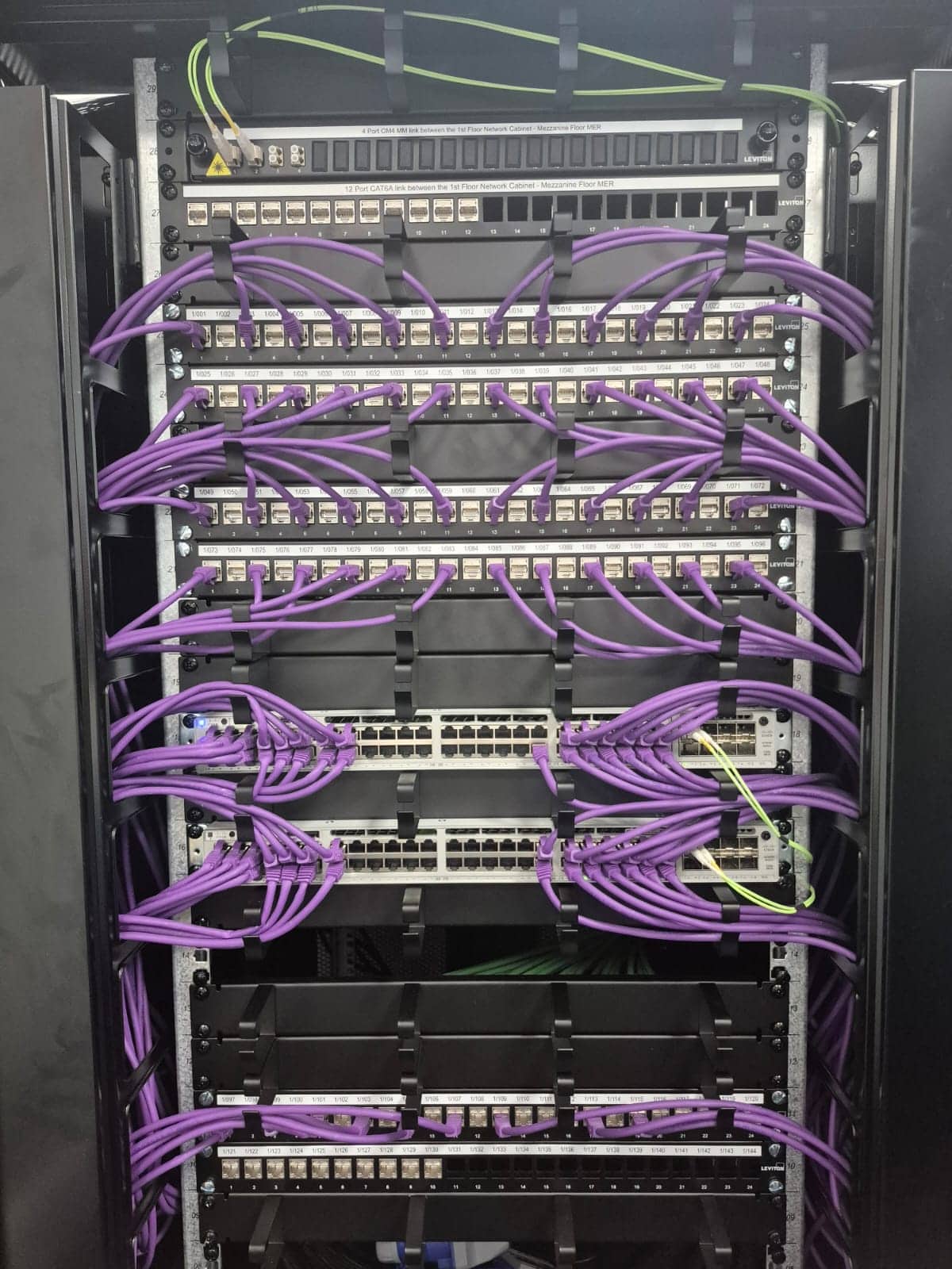 Structured cabling with purple Ethernet cables in a data cabinet.