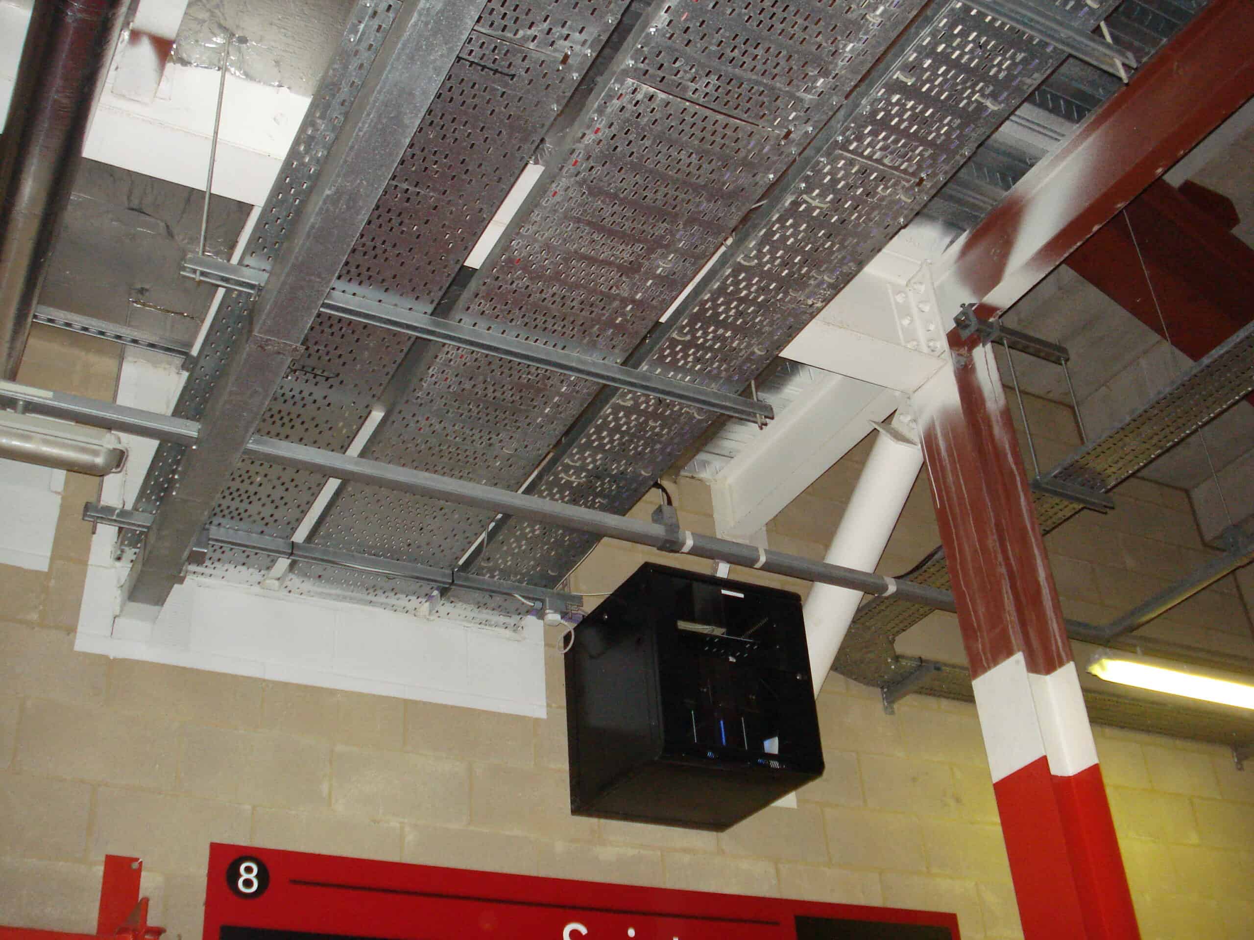 Cable containment on tray above the public concourse at Southampton FC's St Mary's Stadium, next to a wall-mounted network cabinet