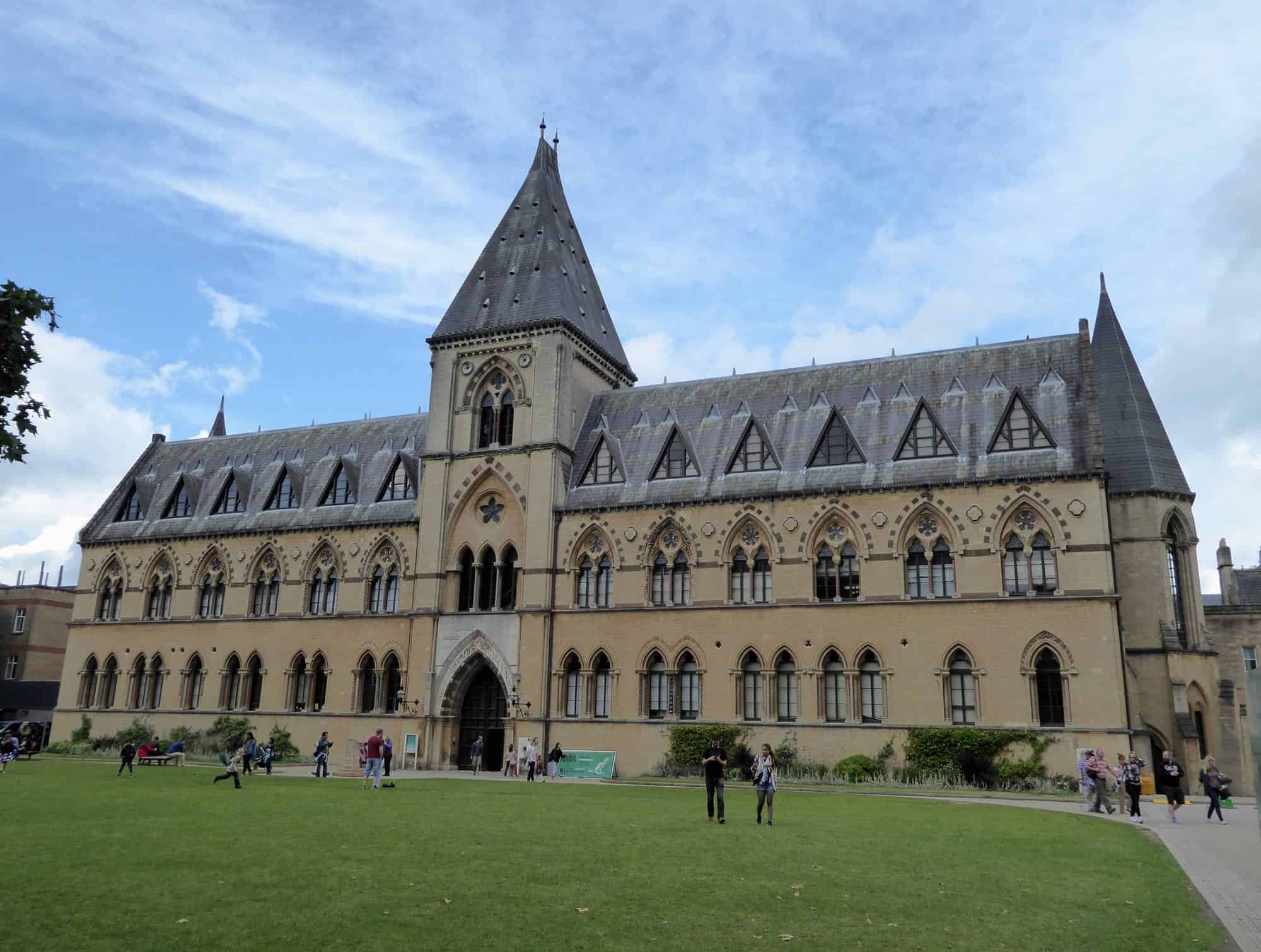 Gothic church with tall spire and arched windows in a city park.